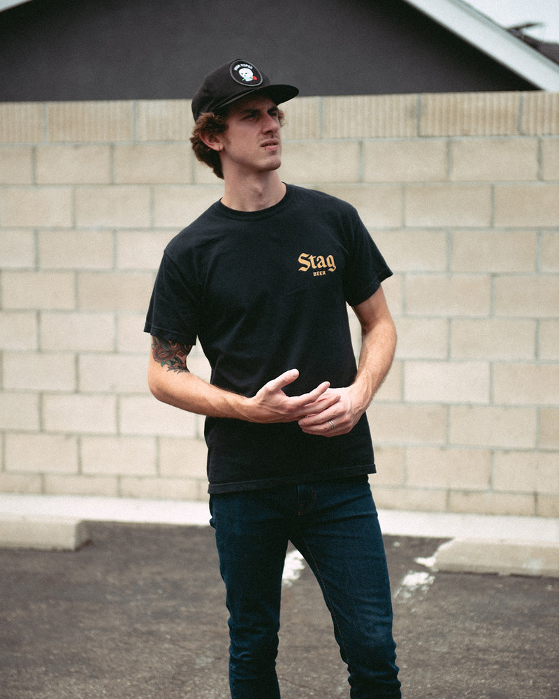 front of black t-shirt with Gold Stag Beer on the left chest on a male model