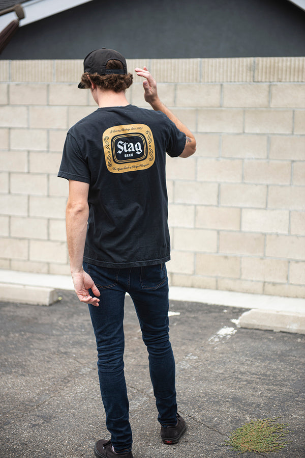 back of black t-shirt with Gold Stag Beer Badge on male model